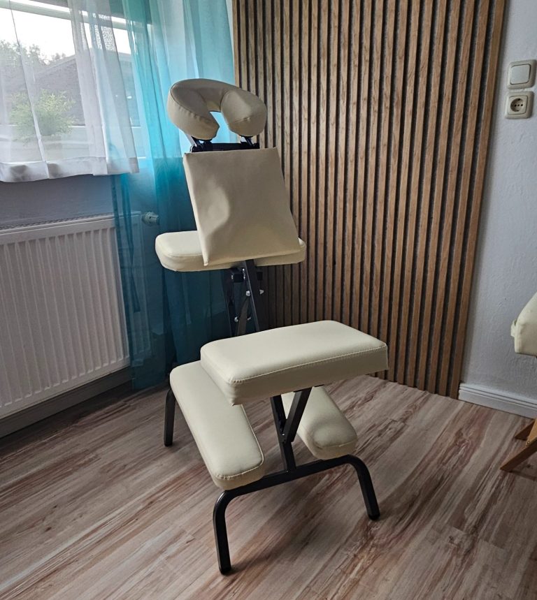 Beige Massagestuhl mit Kopf-, Rücken- und Sitzpolster in einem Raum mit Holzverkleidung.